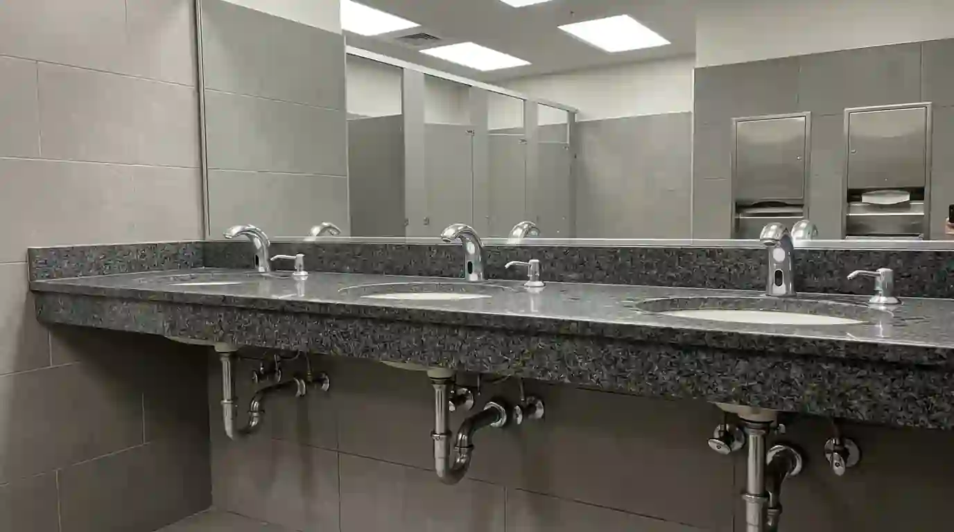 Commercial restroom row of sinks and flush valves in a small office building