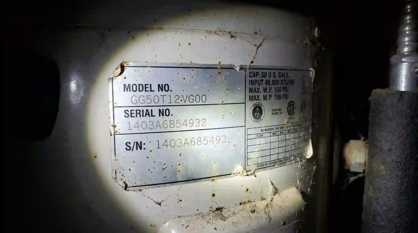 Close view of a water heater rating label with serial number in a garage under a flashlight